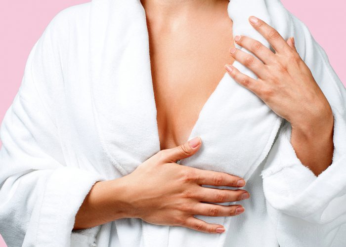 Body care concept. Beautiful woman after bath in white bathrobe on pink background.